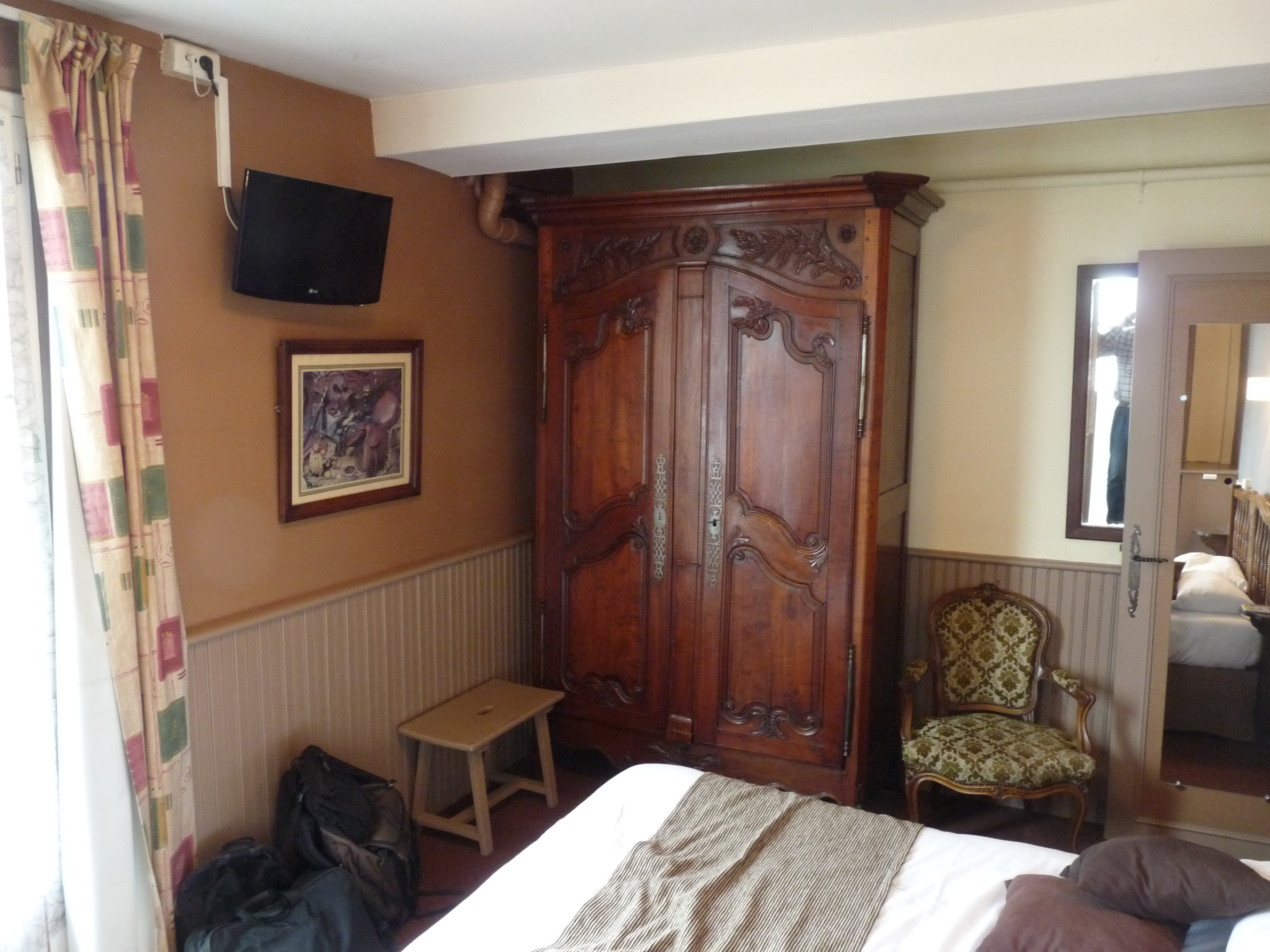 Compact hotel room with a made bed, clear walkway, and writing desk.