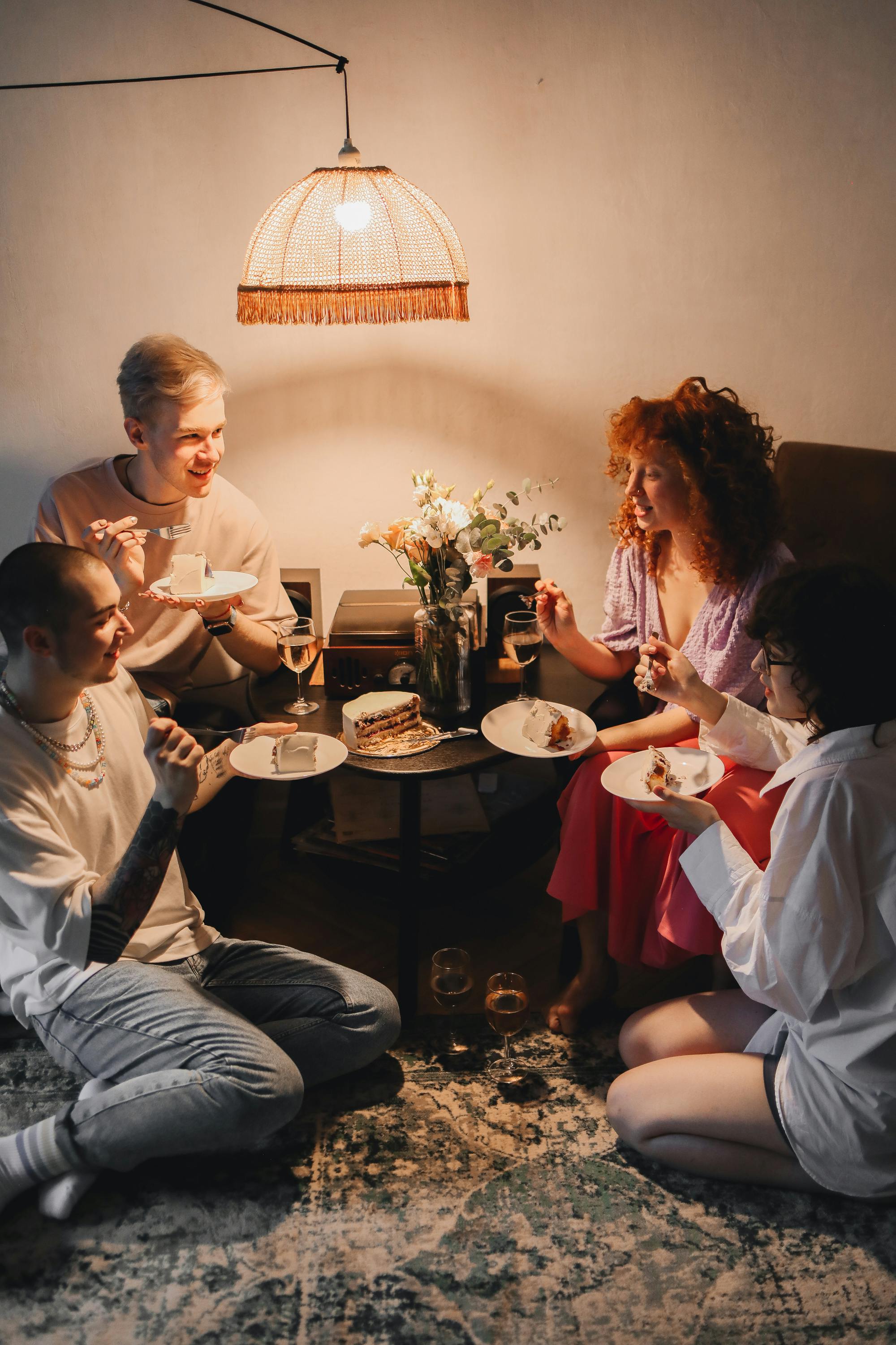 Guests gathered around a small table with cake during a house party.